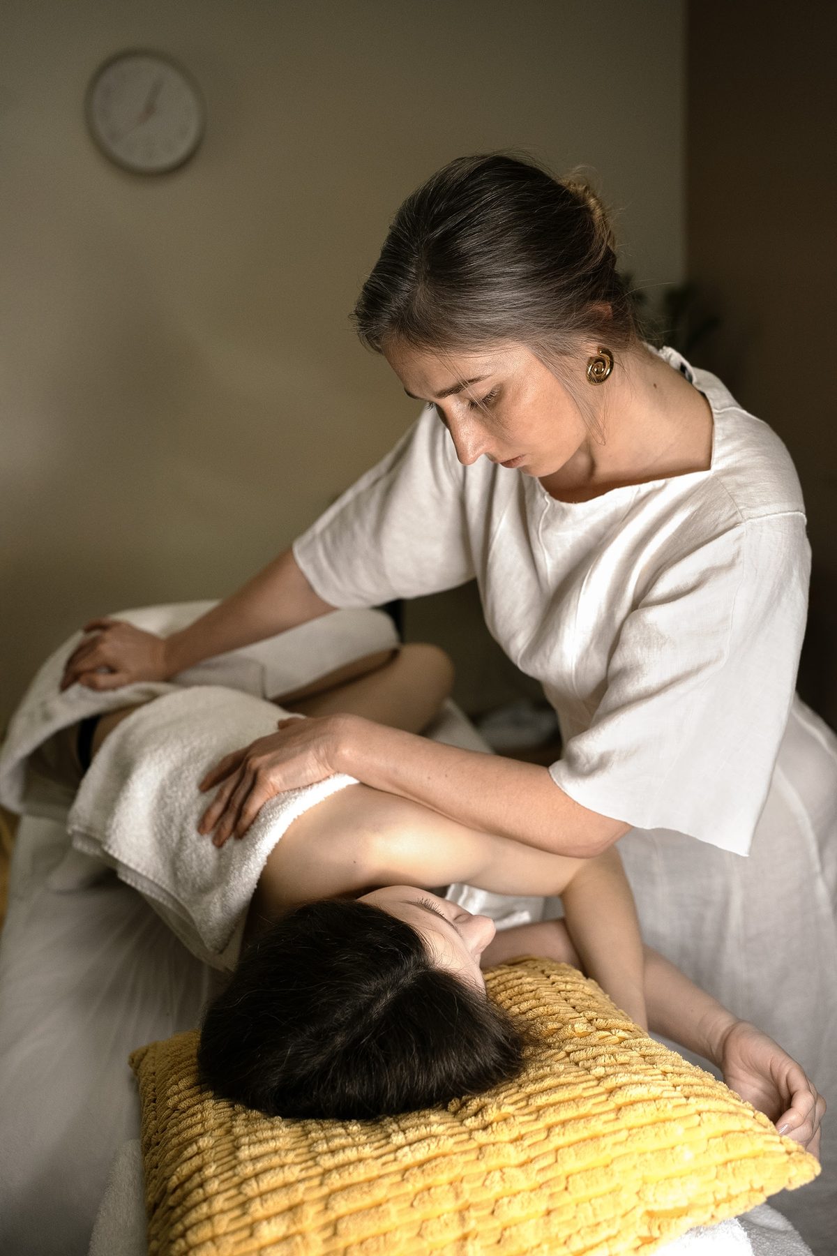 Hanna behandelt een cliënte op de massagetafel, met het hoofd op een geel kussen