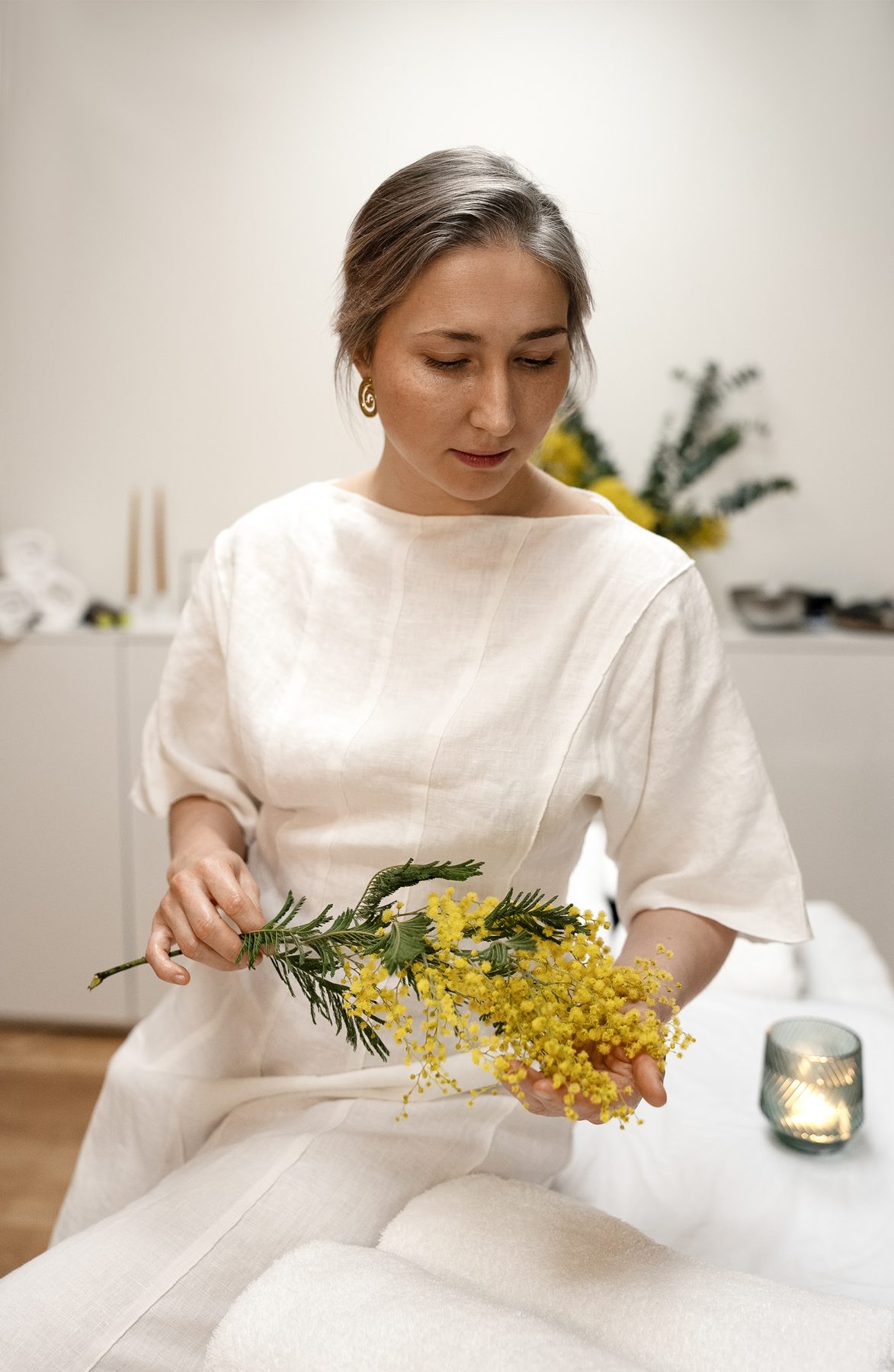 Hanna in een witte tuniek met een bos mimosa in haar handen